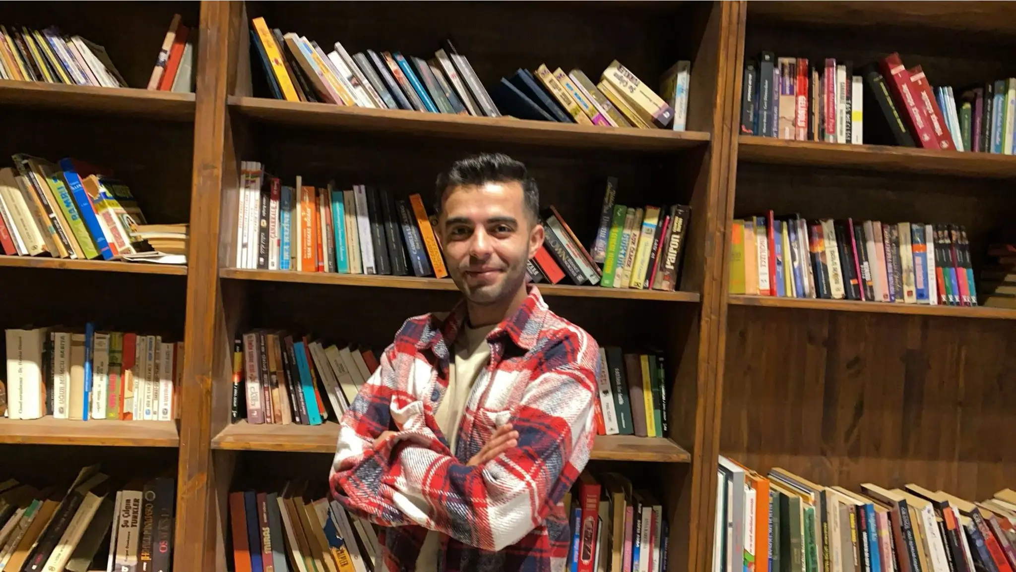 Tolga Akçalının görseli kitapların önünde.